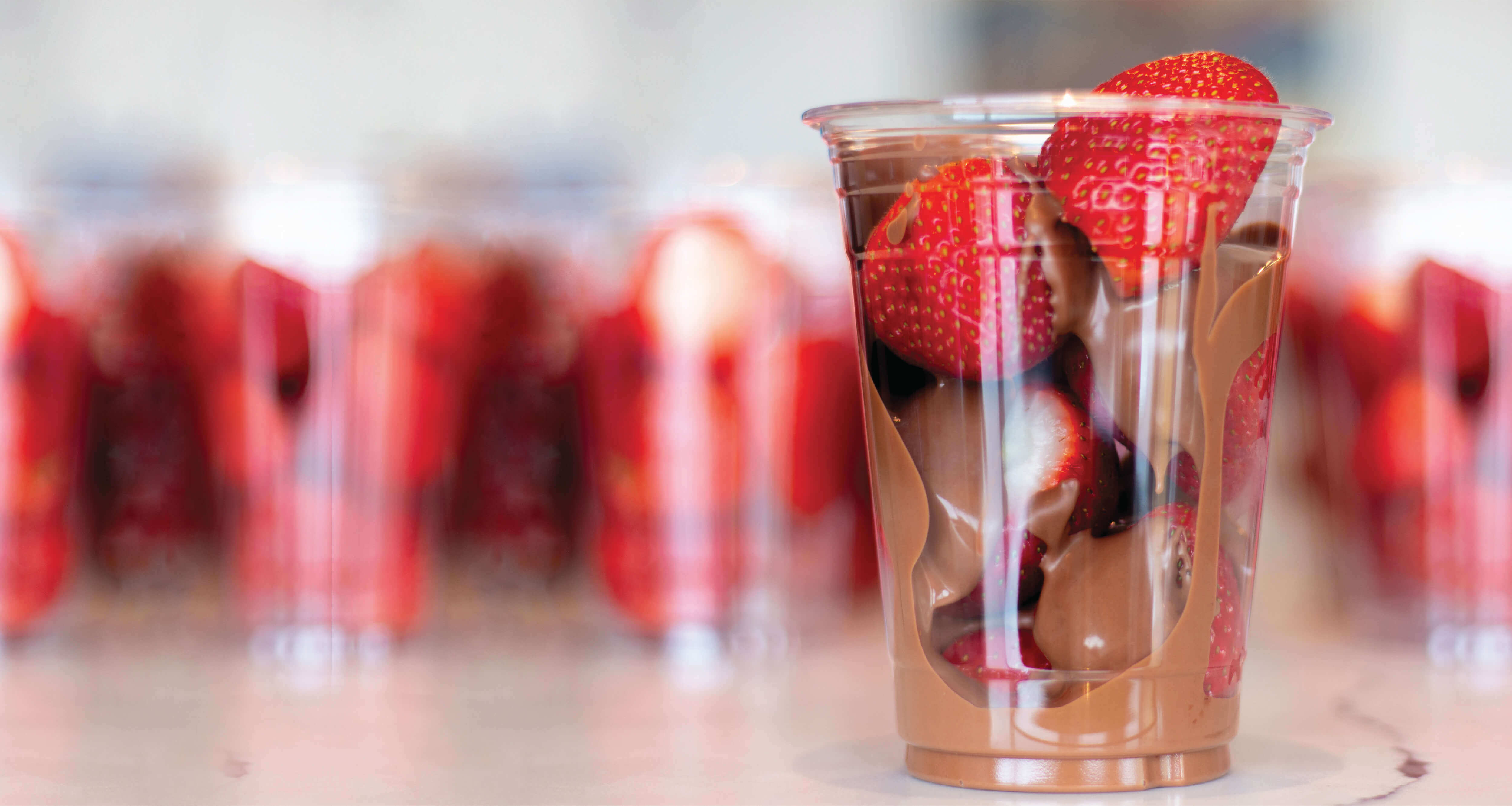 strawberries covered in chocolate in a clear cup